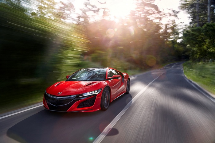 Red Honda NSX driving on a forest road