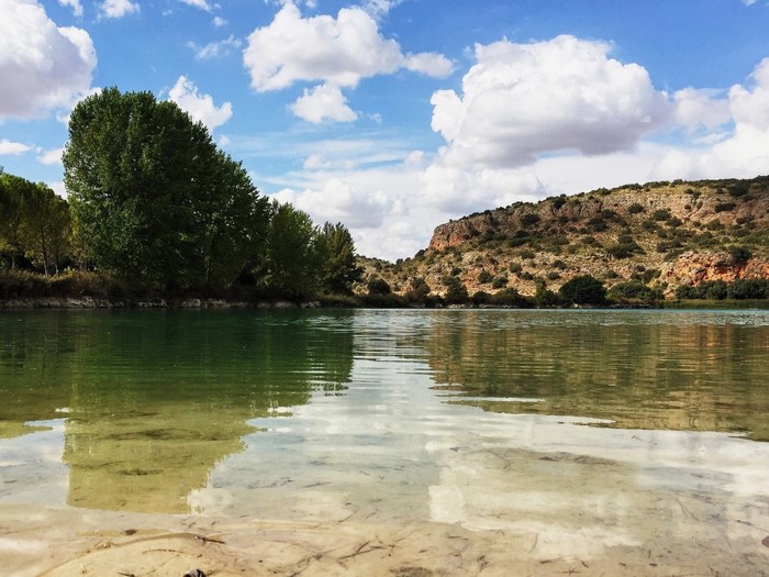 Lake with trees and rocky hills under a cloudy sky