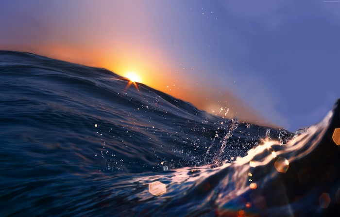 Ocean wave at sunrise with sun rays