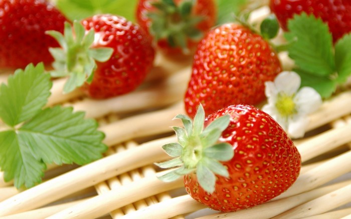 Strawberries and leaves on a woven surface