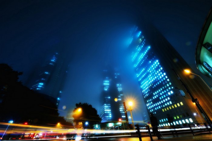 Cityscape at night with skyscrapers and light trails