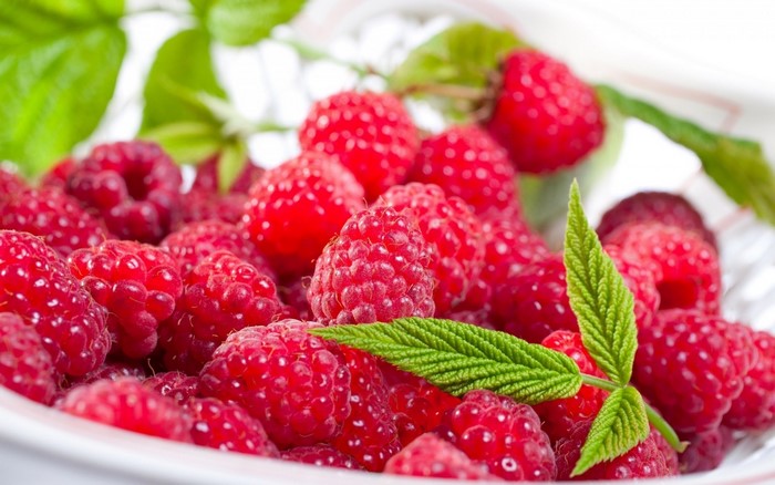 Close-up of fresh raspberries with green leaves