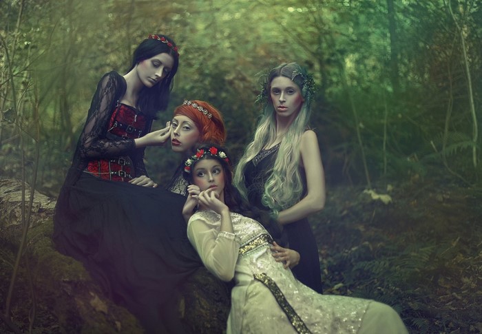 Four women in fantasy attire in a forest