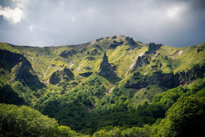 Green mountain landscape with rocky peaks and forest