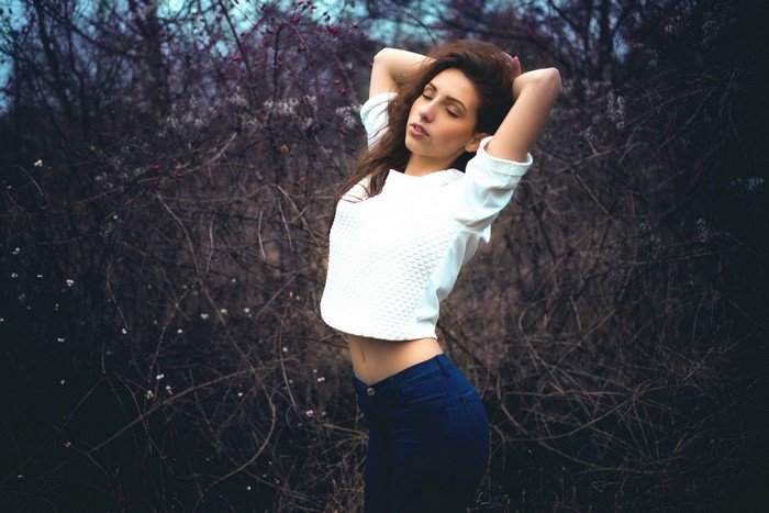 Woman with arms up in a white top and blue jeans