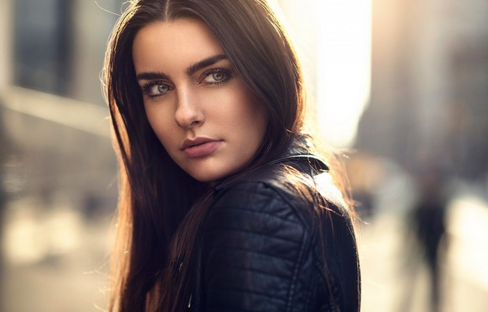 Woman with long brown hair wearing a black leather jacket