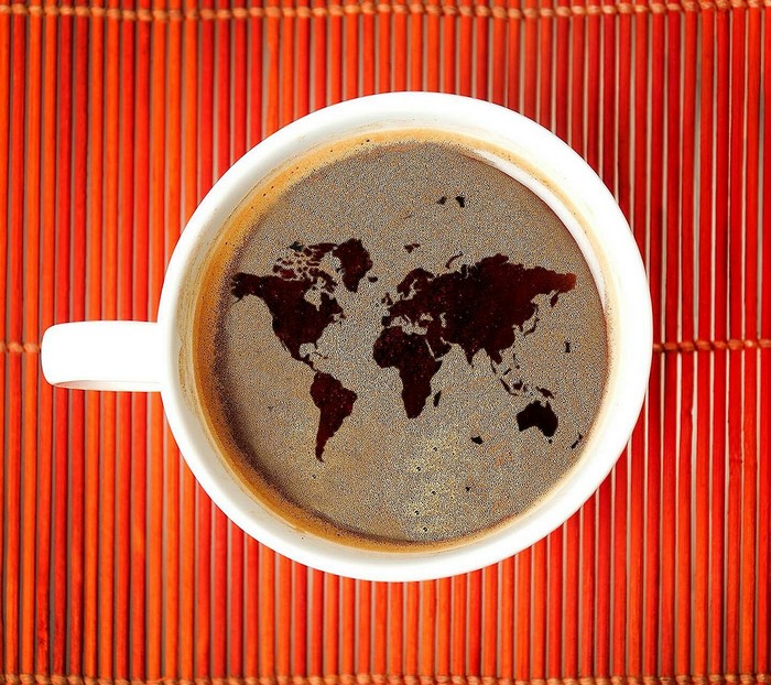 World map in a coffee cup on a bamboo mat