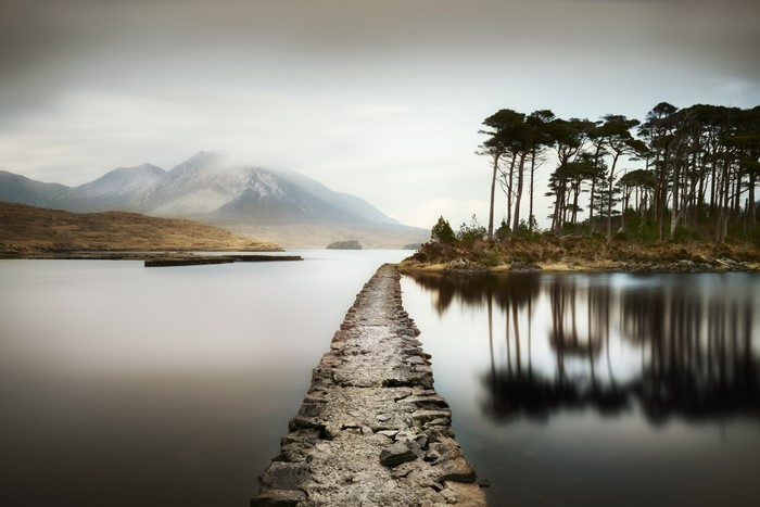 Stone path leading to island with trees and mountains