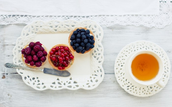 Berry tarts and tea on a white tray