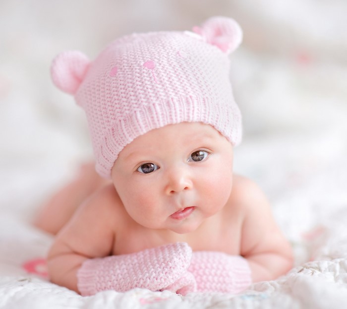 Baby wearing a pink knitted hat and mittens