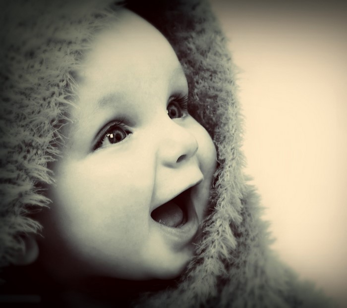 Close up of a baby's happy face in a furry hood