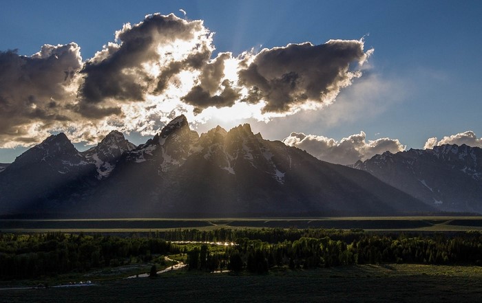 Sunbeams through clouds over mountains and river valley