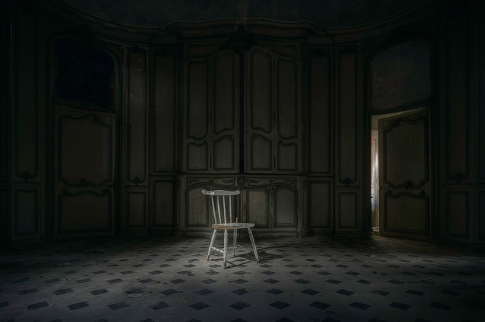 Abandoned mansion room with a single chair