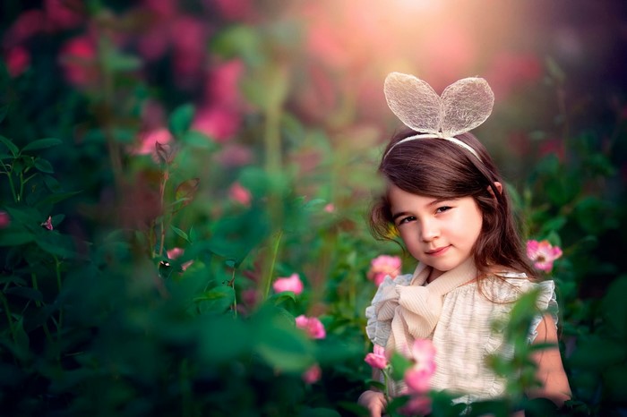 Young girl with bunny ears in a rose garden