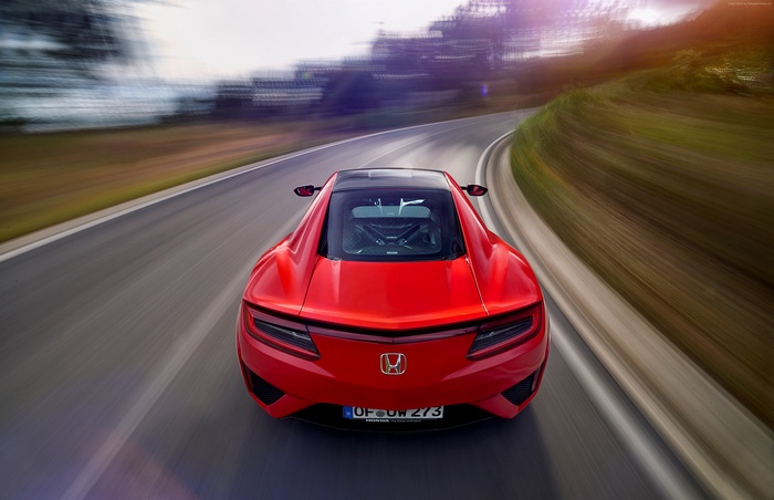 Red Honda NSX driving on a winding road