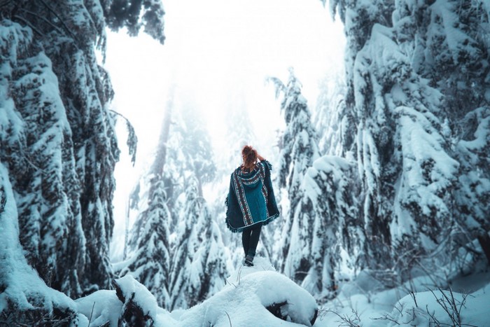 Woman in poncho in snowy forest