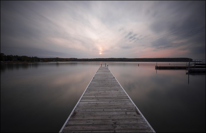 Wooden dock on a calm lake at sunset