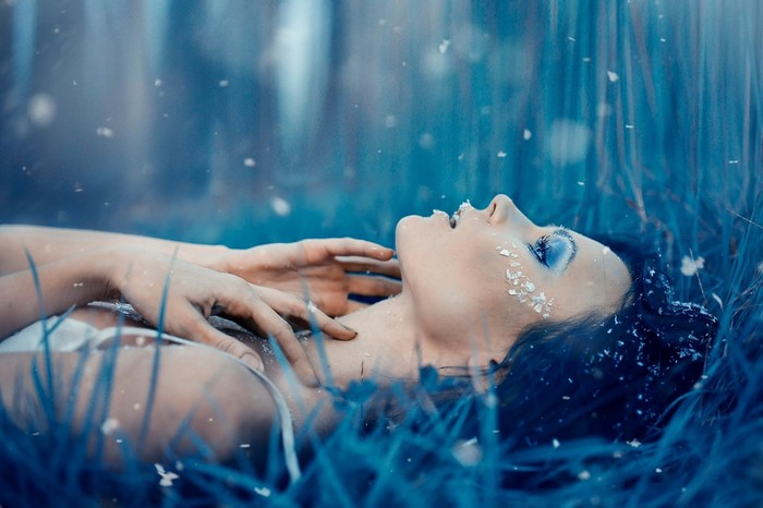 Woman lying in blue grass with petals