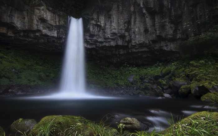 Waterfall cascading into a dark pool in a rocky grotto