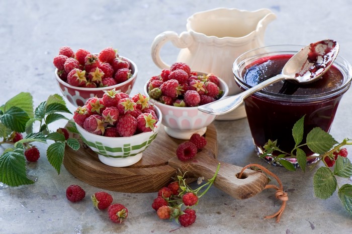 Raspberries and raspberry jam in bowls and jar