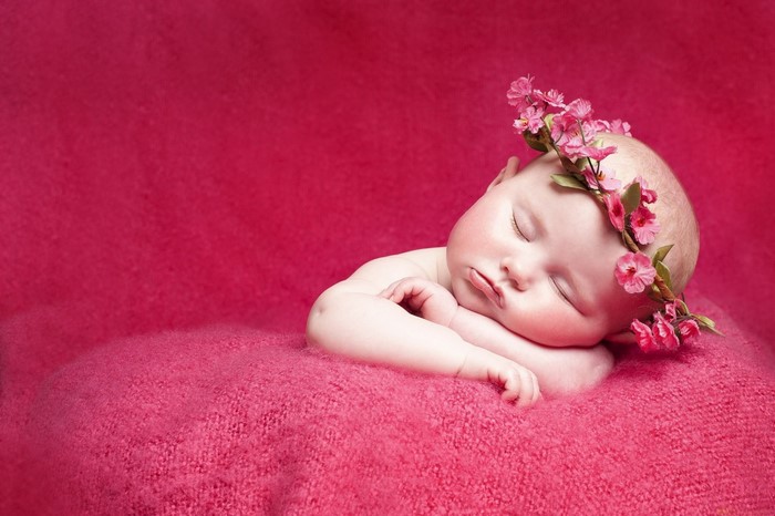 Baby girl sleeping with flower crown on pink blanket