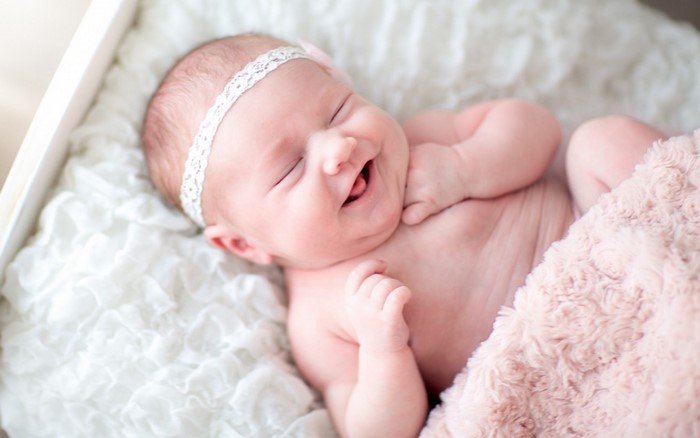 Baby wearing a lace headband and pink blanket