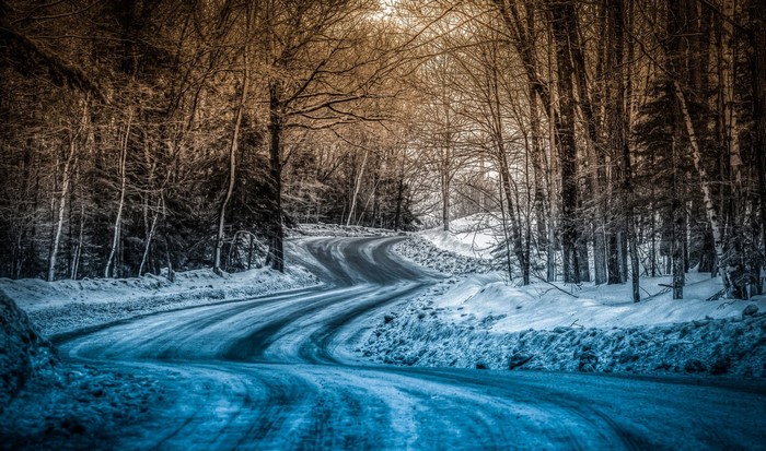 Winding snowy road through a winter forest