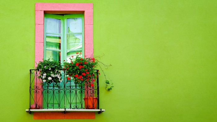 Green window with pink frame and flowers on balcony