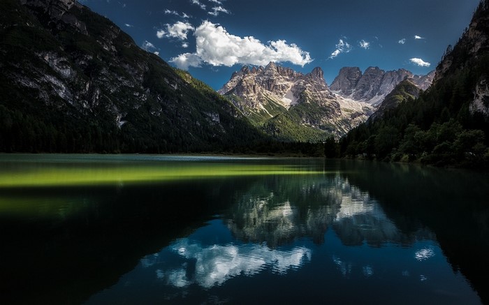 Lake reflecting mountains and clouds in the Alps