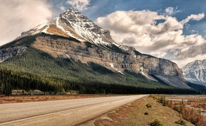 Mountain road with snow-capped peak and forest
