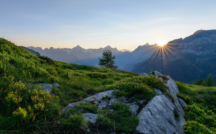 Sunrise over a mountain range with green hills