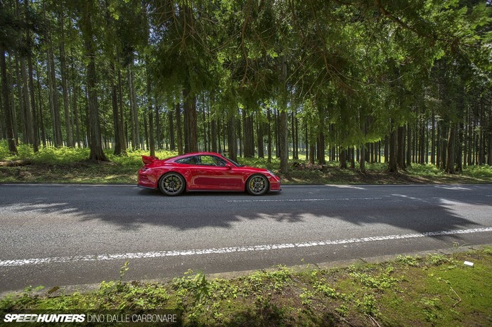 Red Porsche 911 GT3 parked on a road in a forest