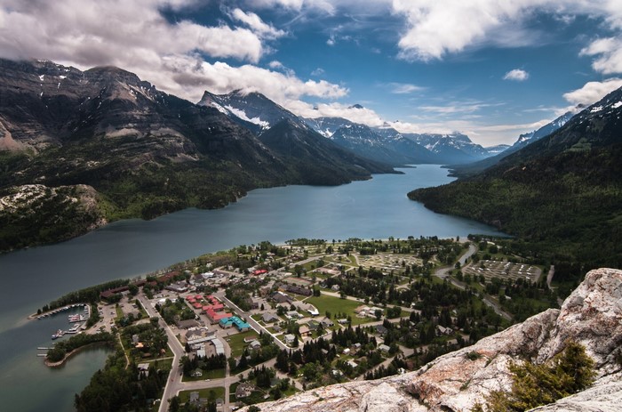 Aerial view of a town nestled beside a lake and mountains