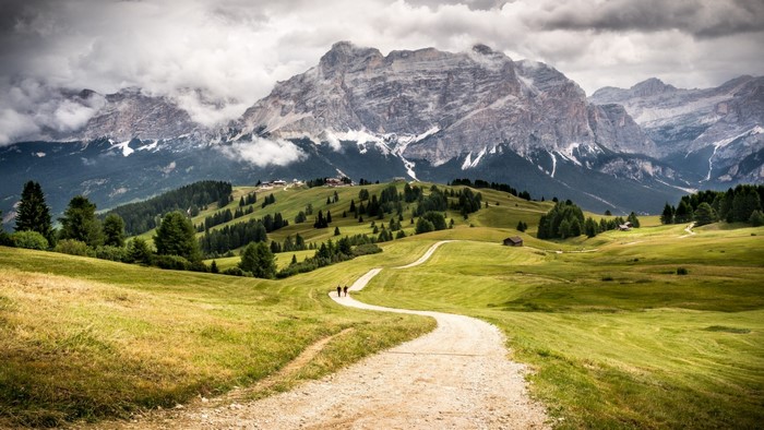 Winding path through green hills towards a majestic mountain range