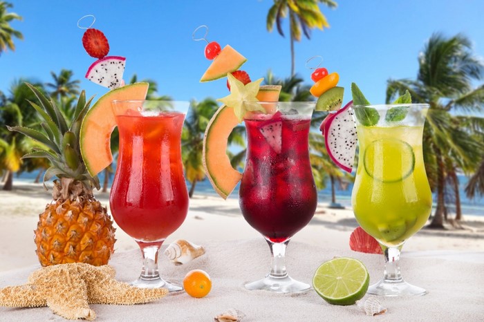 Tropical cocktails on a sandy beach with palm trees