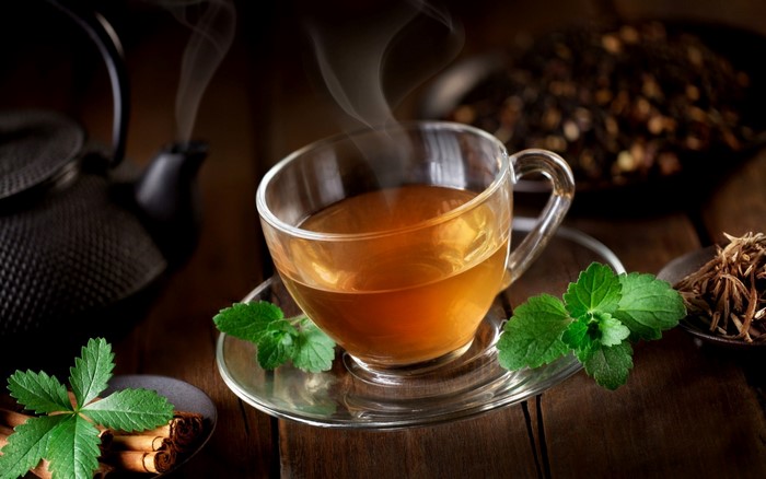 Steaming cup of herbal tea with mint and cinnamon