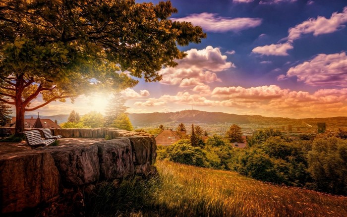 Scenic overlook with benches and a distant town at sunset