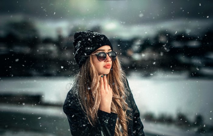 Woman in sunglasses and beanie in the snow
