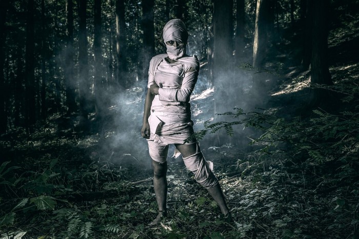 Woman dressed as a mummy in a dark forest