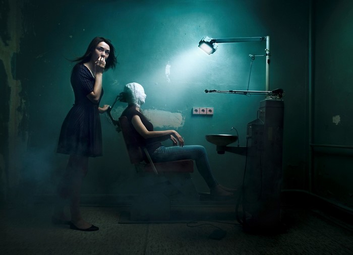 Two women in a dark, eerie room with dental equipment