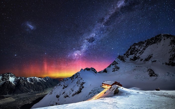 Snowy mountains under the Milky Way and aurora