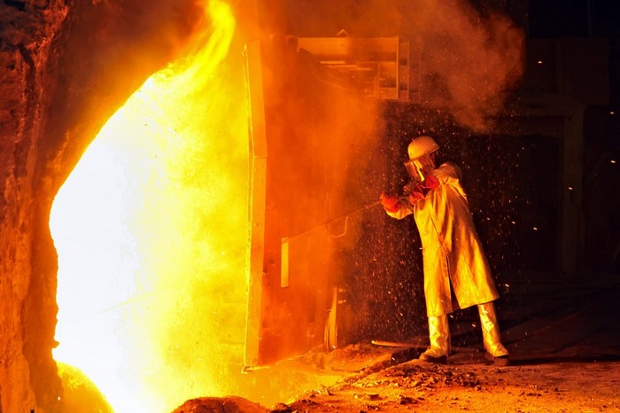 Worker in protective gear near molten metal