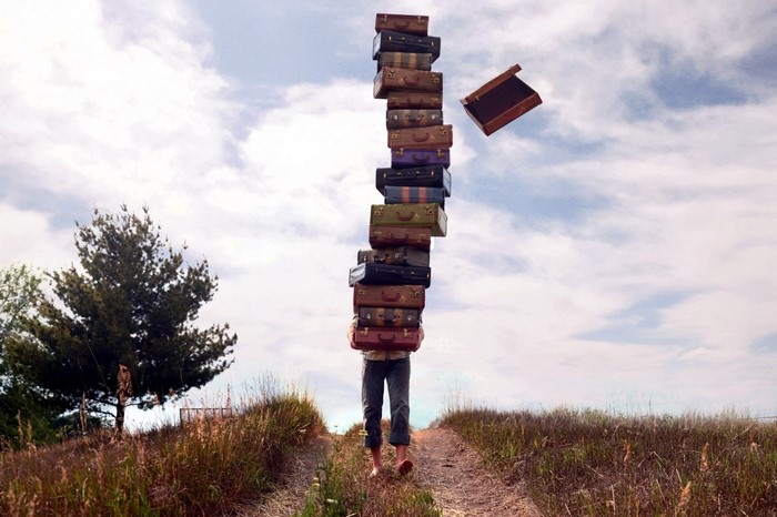 Man carrying a tall tower of suitcases outdoors