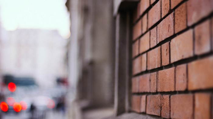 Close-up of a brick wall with blurred city lights in the background