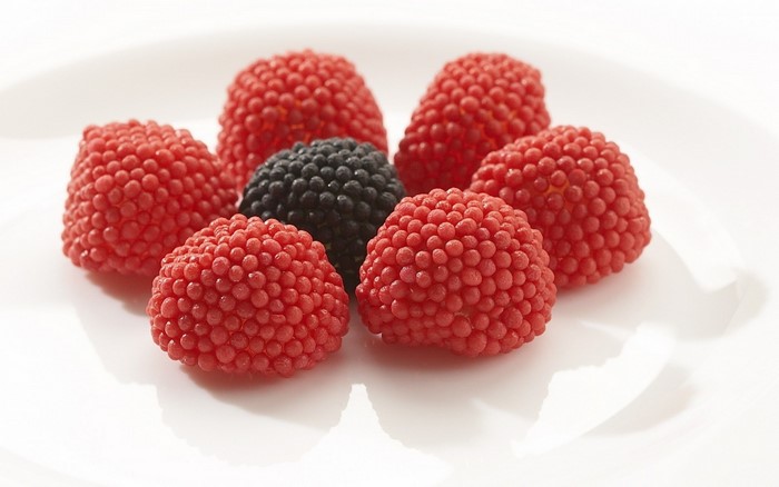 Raspberry and blackberry candies on a white plate