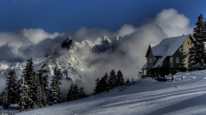 Snowy cabin in the mountains with clouds