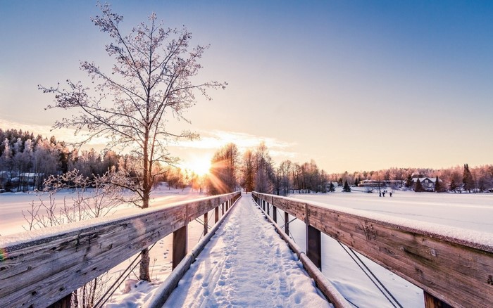 Snowy bridge at sunrise with sun rays