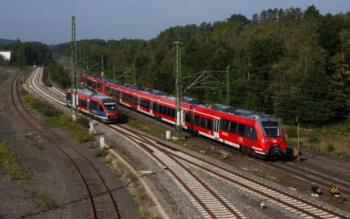 Two trains on railway tracks with trees in background