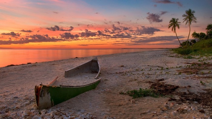 Old canoe on a beach at sunset