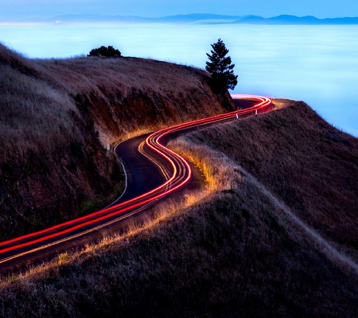 Winding road with light trails on a hill at dusk